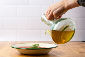 Hand pouring olive oil onto a Mediterranean diet plate

