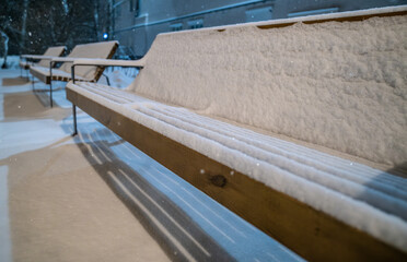 A bench under the snow on a winter evening.