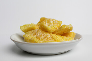 Dried pineapple sweets. Candied and dried pineapple. On small white plate. Isolated on white background