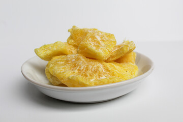 Dried pineapple sweets. Candied and dried pineapple. On small white plate. Isolated on white background