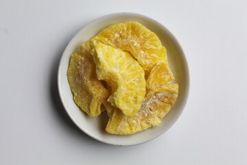 Dried pineapple sweets. Candied and dried pineapple. On small white plate. Isolated on white background, flat lay or top view