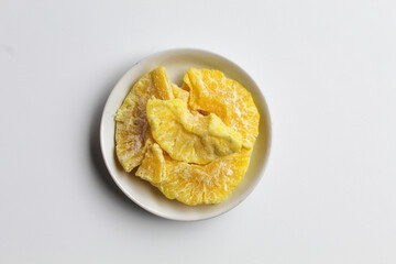 Dried pineapple sweets. Candied and dried pineapple. On small white plate. Isolated on white background, flat lay or top view