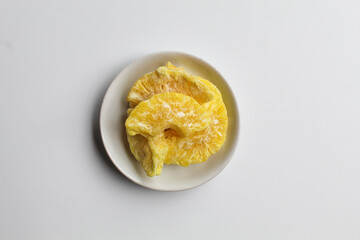 Dried pineapple sweets. Candied and dried pineapple. On small white plate. Isolated on white background, flat lay or top view