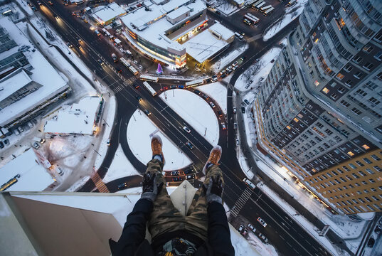  Legs of man sitting on high building rooftop at winter