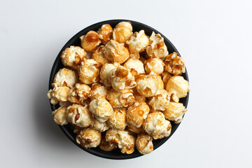 Caramel popcorn, in a black bowl, isolated on white background, flat lay or top view