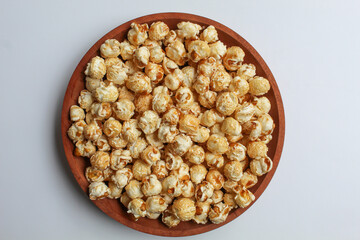 Caramel popcorn, on wooden plate, isolated on white background, flat lay or top view