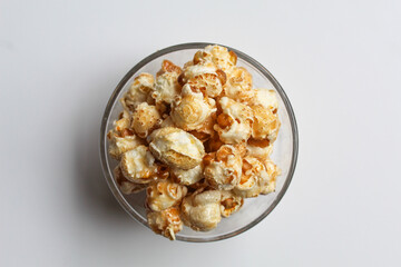 Caramel popcorn, in a transparent glass bowl, isolated on white background, flat lay or top view