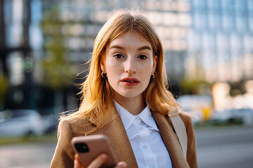 a woman is holding a cell phone in her hand and looking at it