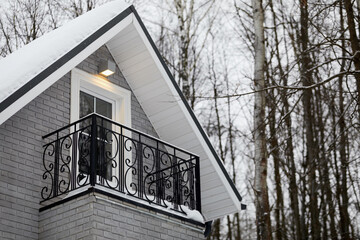 Mansard with balcony and roof covered with snow of house in forest