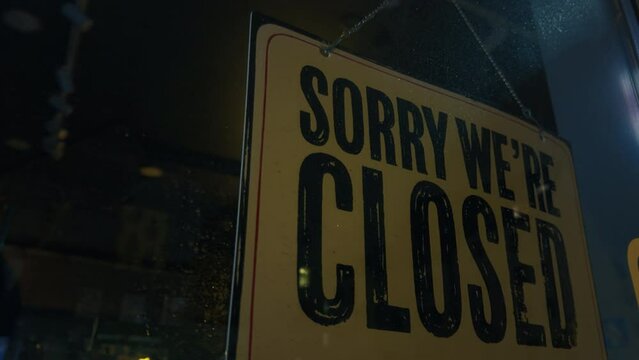 A close up of a sorry we 're closed sign hanging on a window