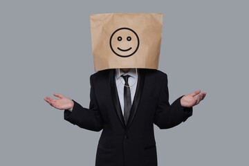 Business person anonymous hiding his head behind happy smile emoticon on gray background
