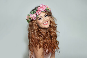 Beautiful woman with make-up, perfect white smile and summer season rose flower wreath on her long healthy shiny wavy hair, fashion beauty studio portrait