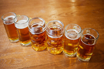 Six glass mugs of beer on wooden table