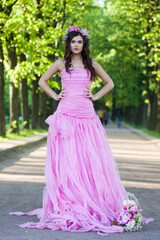 Fototapeta premium Romantic young adult lady with with long hair, make-up and pink flower in spring park. Beauty woman portrait