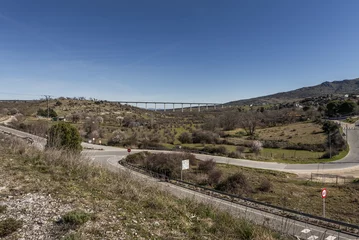 Glasbilder Landwasserviadukt mountain roads and a bridge crossing a valley with sparse vegetation