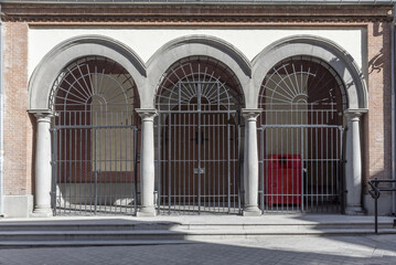 Facade of a church with semicircular arches with black metal bars