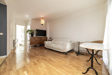 Homely living room with classic wooden furniture, marble table with wrought iron foot and a white leather sofa