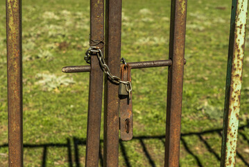 Rusty metal fence of a plot with a chain and a padlock