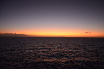 Sunset at sea, reflections of sun rays on rippled water surface, clear sky, concept for traveling and tourism