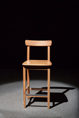 Wooden stool standing spotlighted in studio