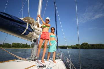 Wandaufkleber Happy woman and girl are on yacht during sailing on river at sunny summer day © Pavel Losevsky
