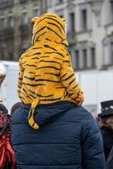 Kind auf den Schultern einer erwachsenen Person betrachtet den Fasnachtsumzug, Luzern, Schweiz
