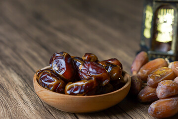 a close-up photo of dried dates served on a wooden bowl and a lantern with Arabic calligraphy...