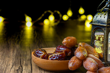 a close-up photo of dried dates served on a wooden bowl and a lantern with Arabic calligraphy...