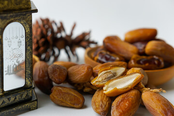 a close-up photo of dried dates served on a wooden bowl and lantern with Arabic calligraphy meaning...
