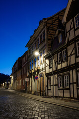 Street alley in the small town of Schwabisch Hall, with houses and buildings with typical German architecture and street lanterns, at night. - 755696152