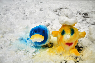 Obraz premium Two funny heads made of snow and painted in different colours