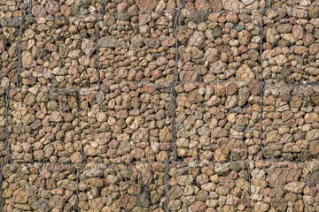 engineering structure made of stones behind metal wire netting to strengthen the river bank near the road bridge