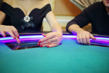 Electronic green table in modern casino and hands of two players