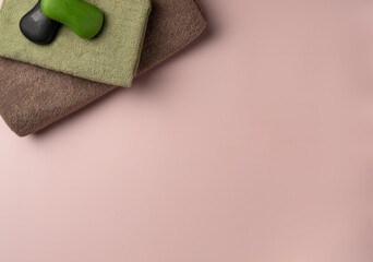Pieces of black and green soap on a towel on pastel pink background. Spa concept