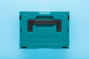 New dark black green professional plastic toolbox for repair tools, equipment or other things on light blue table background. Pastel color. Closeup. Top down view.