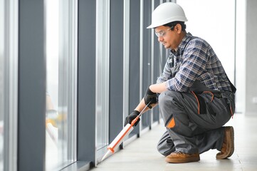 Workman in overalls installing or adjusting plastic windows
