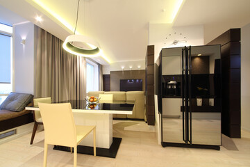 Dining area with a large table and chairs in front of recreation area with a home theater in modern flat