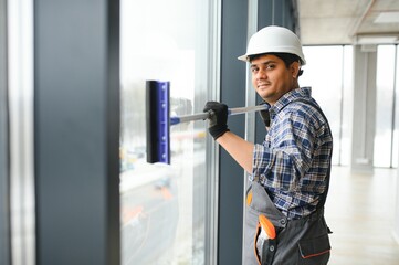Male janitor cleaning window in office