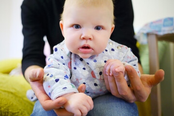 Little funny baby is in hands of father in bedroom, shallow dof