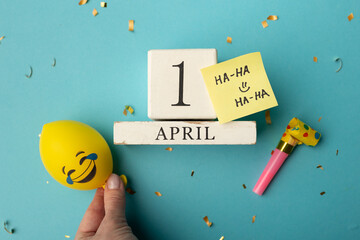 April 1st. Image of april 1 wooden calendar and festive decor on the blue background. April Fool's...