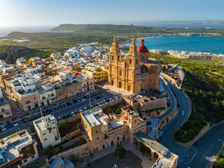 Aerial view of The Parish Church in Mellieha city and road. Blue sky, sea, day. Malta 