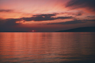 Fototapeta premium Serene Sunset Over Tranquil Waters With Vivid Sky Reflecting in the Calm Sea