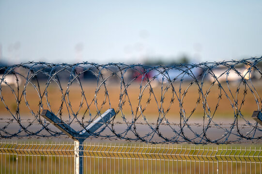 Barbed wire fence on a background of green grass and road. Selective focus