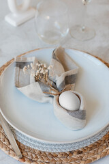 Easter themed table setting, with napkin folded in shape of bunny ears and an egg in the middle