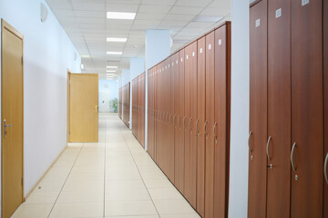 Long corridor with many wooden cabinets and opened door in office