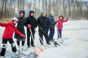 Three adults and three children going to clean outdoor skating rink surface from snow