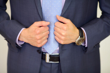 Hands of man in suit with tie, leather belt and wristwatch in studio, noface