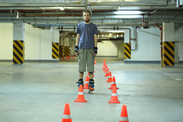 Roller skater stands near orange cones in empty underground parking
