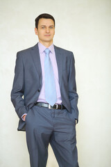 Handsome brunet man in business suit with tie poses in studio
