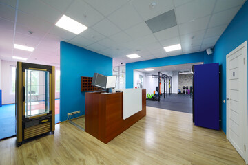 Reception with wooden counter and blue walls in modern fitness center